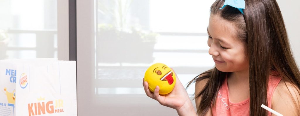 Girl holding Burger King Emoji toy